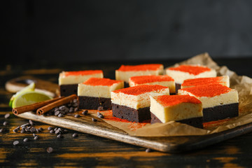 Spiced chocolate cake with cream, on a wooden board with lime and cinnamon stick.