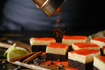 Spiced chocolate cake with cream, on a wooden board with lime and cinnamon stick.