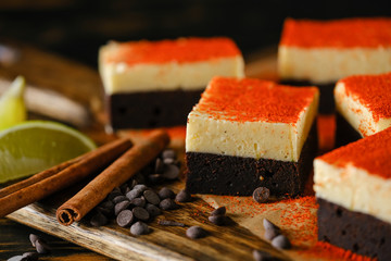 Spiced chocolate cake with cream, on a wooden board with lime and cinnamon stick.