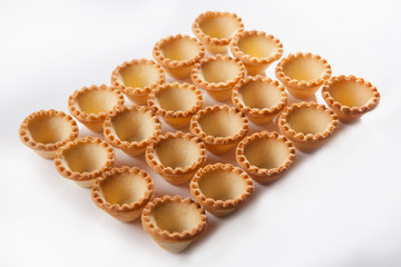 Obraz na płótnie Canvas A large number of tartlets on a white background. Empty forms for filling. An isolated object.