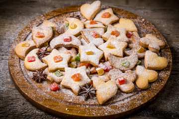 Holiday cookies with icing and candied fruit on wooden dish