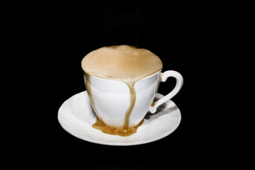 black coffee poured from a white mug on a dark background