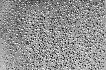 A grey metal background of steel sheet with shiny surface. Large drops of water on it