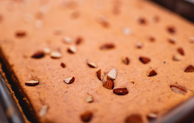 Close up of top layer of freshly baked Indian eggless tea cake topped with chopped almonds, healthy homemade cake background image. Defocused picture of dry cake for bakery design layout template.
