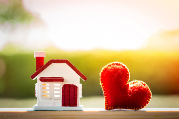 Home model and red heart put on the wood on sunlight in the public park, For family love concept.
