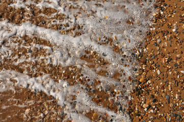 Sand, rocks and foam on the resort beach close-up