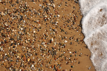Sand, rocks and foam on the resort beach close-up