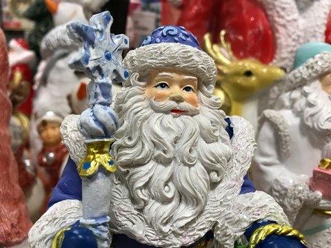 Portrait of a toy Santa Claus in a blue suit on the background of a zoot deer and other toys in the store. Photo with mobile under shop lighting.