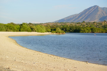 the atmosphere of the beach or the coast before the afternoon with calm waves and sunny weather set against the background of the high seas and mountains or plateaus