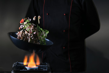 Flying mixed vegetables on a pan. Black background for copy text. Сooking in a wok pan. Diet healthy food.