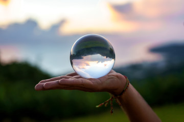 Hand of a young magician guy holding a glass ball for contact juggling at sunset