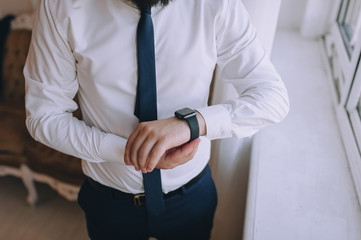 Male businessman holds hands for a smartwatch. Business. The morning of the groom. A young guy looks at his watch and is going to work. Modern technology. Photography, concept.
