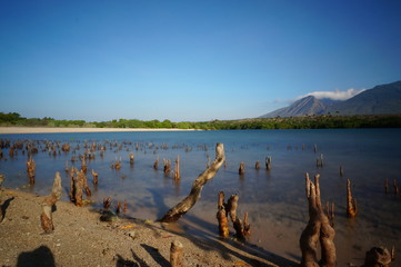 the atmosphere of the beach or the coast before the afternoon with calm waves and sunny weather set against the background of the high seas and mountains or plateaus