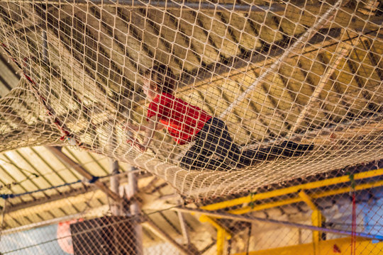 Boy crawls on a net in an obstacle course