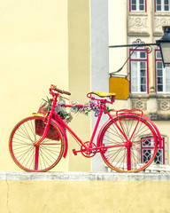 Vintage old red bicycle decorated with flowers and a basket. Street retro decor in Europe.