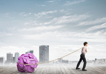 Man pulling with effort big crumpled ball of paper as creativity sign