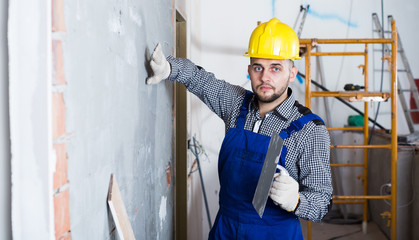 Professional builder is checking the quality of the work done after the plaster wall