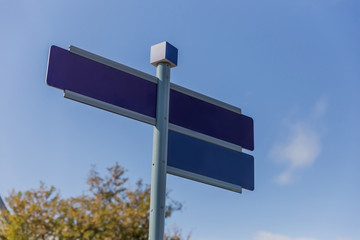 Information. Blue empty direction indicator on blue sky and tree background