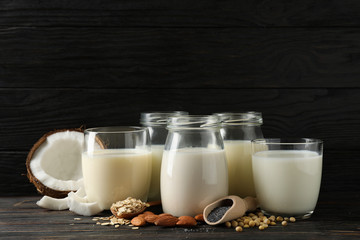 Glasses with diferent types milk on wooden background, space for text