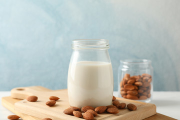 Glass of almond milk, almond seeds on white table again blue background, space for text. Closeup