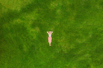 Junge Frau liegt mitten auf einem Feld und entspannt sich, Drohnenfoto
