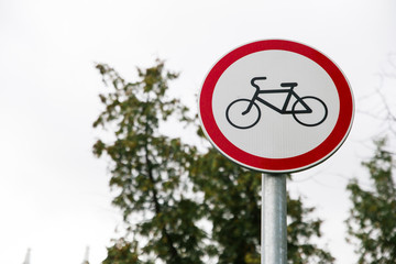 white with red border round road sign No Cycling close-up on a blurred background of sky, trees