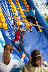 Friends climbing on inflatable slide in amusement park