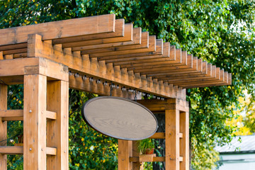 brown wooden oval sign closeup on a wooden fence on the background of trees in summer