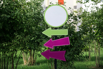 one round plastic white with a green edge blank sign and three plastic directional arrows green pink and purple close up