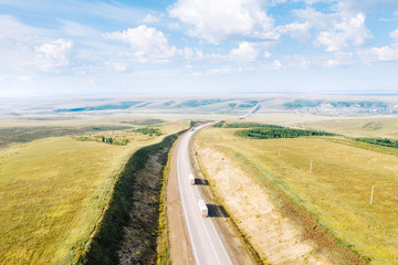 Federal highway P-297 "Amur" in Siberia, aerial view. Trunk road with freight traffic in countryside steppe hills. Trans-Siberian Highway near Chernyshevsk in Zabaykalsky Krai, Russia
