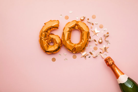 Happy 60th anniversary party. Champagne bottle with gold number balloon.