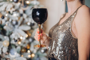 Festive female hand in bright party clothes holding goblet of alcohol beverage close-up. Attractive...