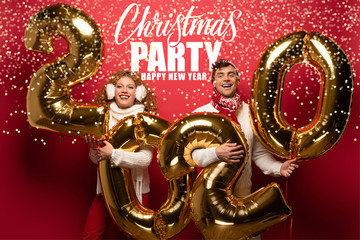 beautiful couple in winter outfit holding new year 2020 golden balloons on red with Christmas party, happy new year lettering