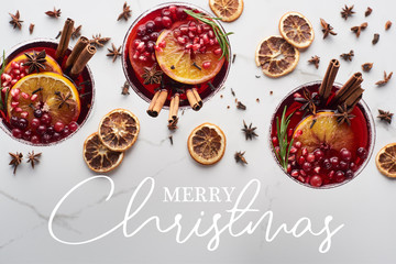 top view of christmas cocktails with orange, pomegranate, cinnamon with merry christmas illustration