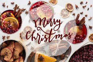 top view of christmas cocktails with orange, pomegranate, cinnamon, pie on tray, dry apples and frozen cranberry with merry christmas illustration