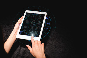 cropped view of astrologer holding digital tablet with zodiac signs on black velvet cloth