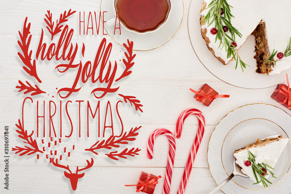 Sticker top view of christmas pie on white wooden table with cup of tea, candy canes and little gifts with have a holly jolly Christmas lettering