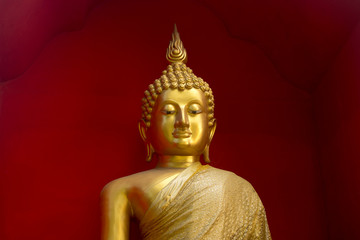 Detail of a Buddha statue with golden cloth and red background. In Wat Buppharam temple, Chiang Mai