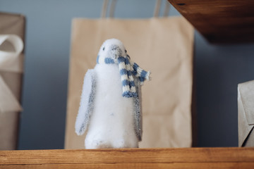 Close-up of light blue toy penguin on brown wooden shelf.