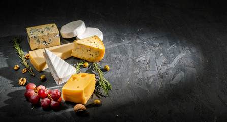 Different sorts of cheese. Cheese platter with different cheese, and spices on dark background. Top view, wiht copy space