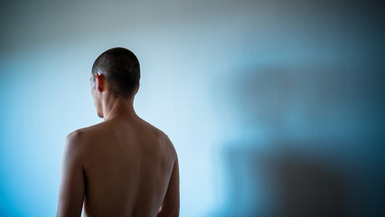 Espalda desnuda y silueta de joven con la cabeza rapada