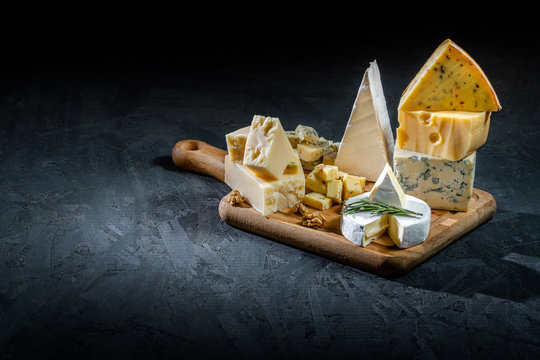 Different sorts of cheese. Cheese platter with different cheese, and spices on dark background. Top view, wiht copy space