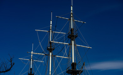 Masts of a ship without sails against the blue sky