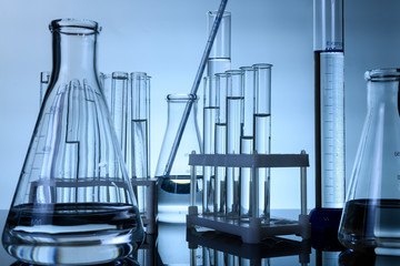 test tubes and flasks stand with clear liquids on a table in a laboratory