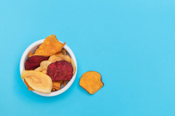 Various handmade vegetable chips on blue background