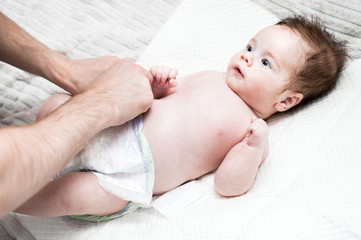 young dad puts a fresh diaper on his baby. Close-up. Newborn care concept. Dad does hygiene to his...