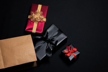 Top view of black gift box with red and black ribbons isolated on black background.