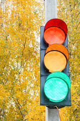 traffic lights with all three colors Illuminated on cement pillar at crossroad on background of...
