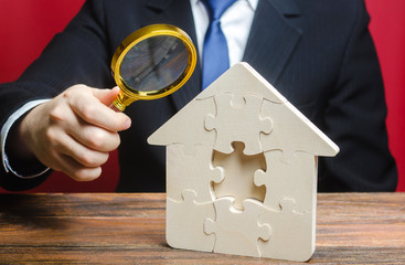 Man studies the missing piece in puzzles house. Purchase or construction comfortable dream home....