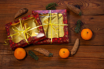 Christmas gift in golden pouch bags, red present box wrapped with New year decorations on rustic wooden background. Trendy tea,coffee packaging mockup, flatlay style.Copy space,winter holidays concept